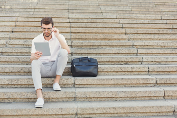 吸引深思的商人在户外使用平板电脑图片下载