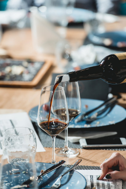 品酒师在品酒时将红酒倒入玻璃杯图片下载