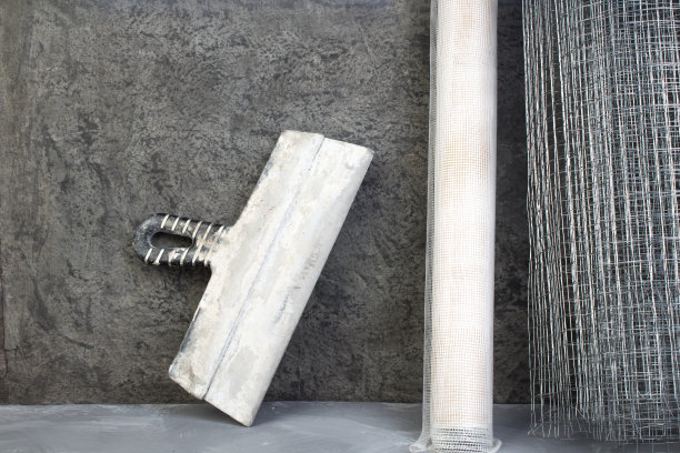 辊网用于抹灰，油灰刀对灰色混凝土背景。副本的空间。俯视图图片下载