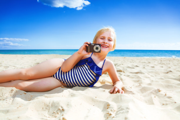 微笑的孩子在海边用数码相机拍照图片下载