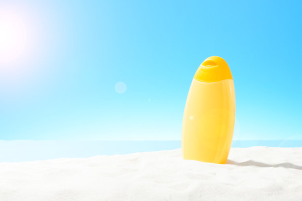 沙滩上的一瓶橙色防晒霜图片下载