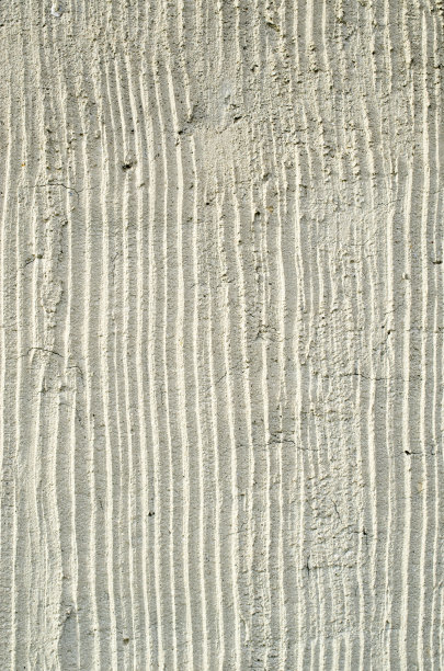 在阳光明媚的日子里，旧的淡褐色石膏在墙上特写图片下载