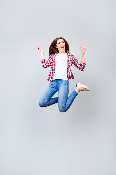 哇!幸福、梦想、乐趣、快乐理念。非常兴奋快乐可爱的黑发女孩正蹦蹦跳跳，穿着休闲的衣服，白色的鞋子，在纯浅蓝色的背景上图片下载