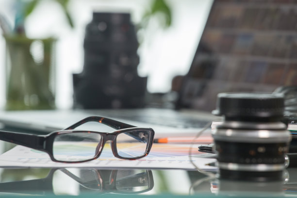 一张桌子上放着一副对焦眼镜、一台笔记本电脑和一些照片镜头图片下载