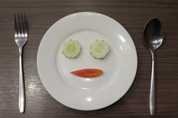 黄瓜和番茄装饰在一个白色的盘子上看起来像脸图片下载