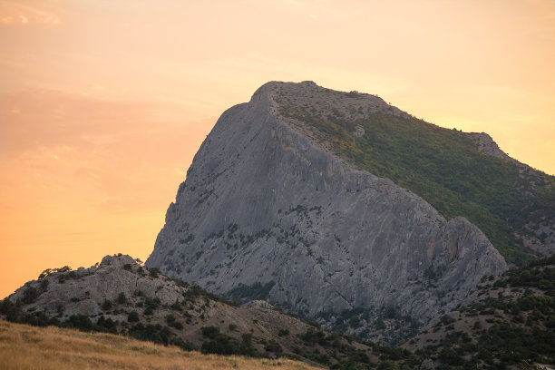 黎明或日落时，最高的山有陡峭的斜坡，天空是淡粉色的图片下载