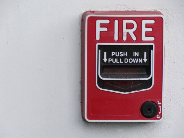 红色火警拉站开关安装在白色墙壁上图片下载