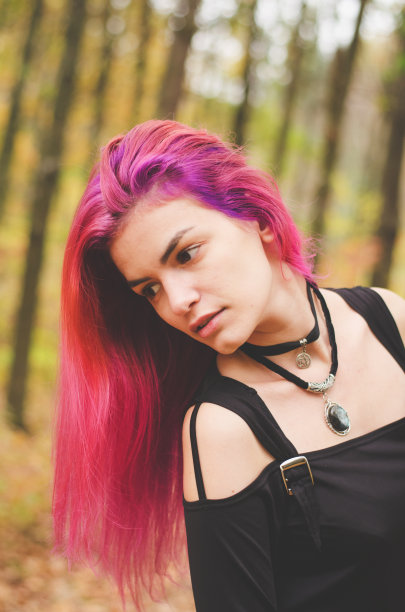 穿着黑衣服的年轻女巫正在森林里施展魔法图片下载