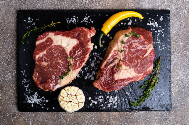 生肉。生牛排放在切菜板上加上迷迭香和香料，俯视图图片下载