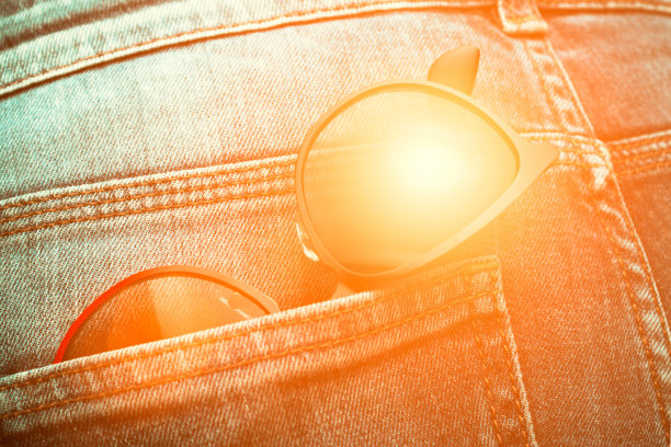 牛仔裤口袋里的太阳镜。阳光闪耀图片下载