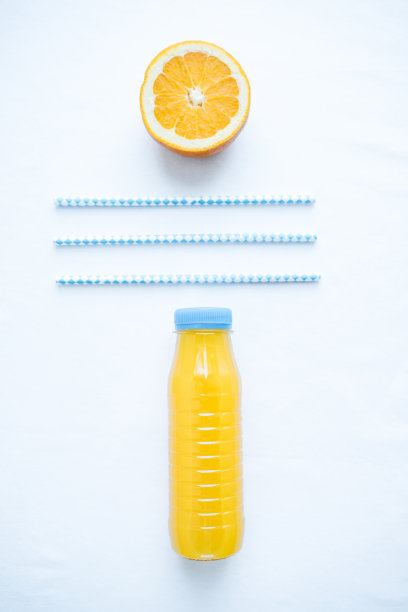 垂直照片的塑料瓶与橙汁和蓝色管在白色的背景图片下载