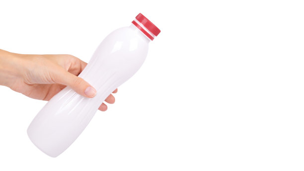 手拿红帽子的酸奶瓶，隔离在白色背景上，健康的生活方式，装牛奶的塑料容器。复制空间、模板图片下载