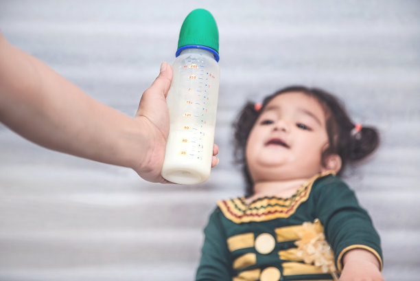妈妈给小女孩一瓶牛奶。素材图片