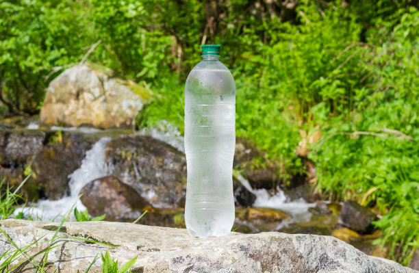 喝水的瓶子靠石头抵着山涧图片下载