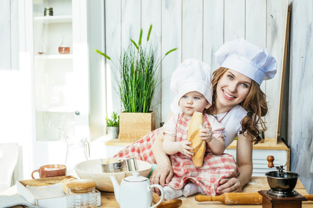 妈妈和宝贝女儿又开心又漂亮，在家里的厨房里准备面点和面粉图片下载