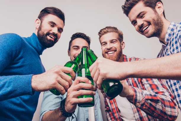 欢呼的男人!单身男人的生活。低角度照片四个快乐的朋友，碰杯啤酒。他们是体育比赛的球迷，如足球，篮球，曲棍球，棒球图片下载