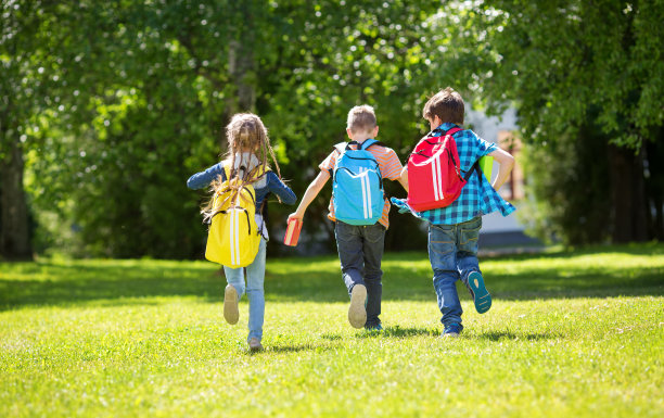 孩子们背着背包站在学校附近的公园里素材图片