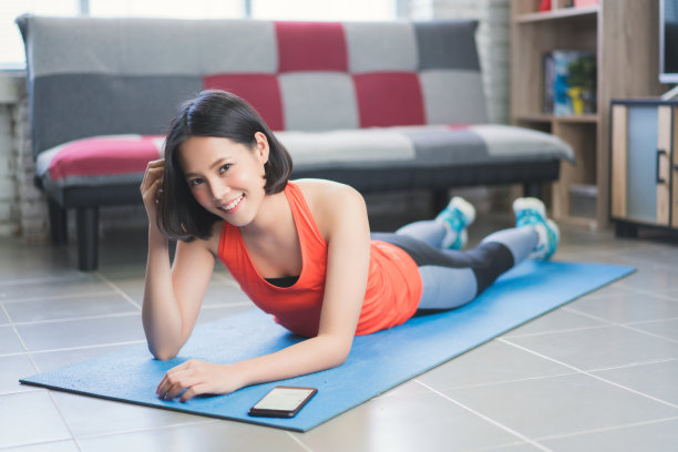 亚洲女性在锻炼后休息和听音乐。她躺在瑜伽垫上图片下载