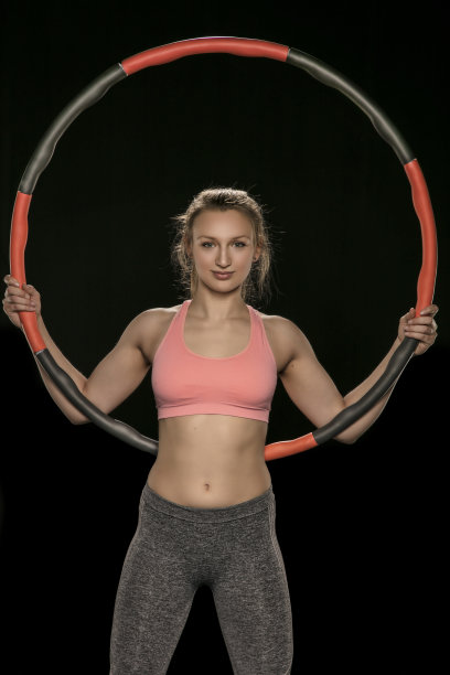 手持呼啦圈的运动女子，孤立在黑色背景中素材图片