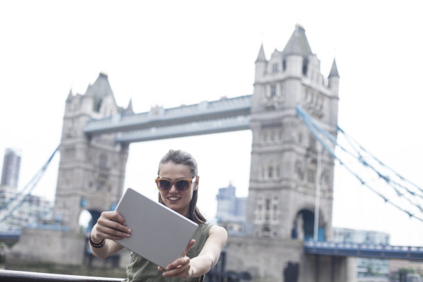 一名年轻女子在塔桥上用平板电脑自拍图片下载