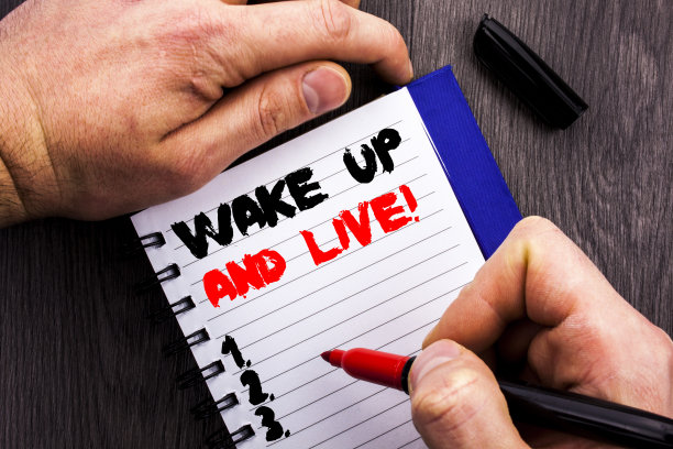 手写的文字标志显示醒过来和生活。概念照片励志成功梦想生活挑战写在笔记本上的书，男人写作握笔木制背景。图片下载