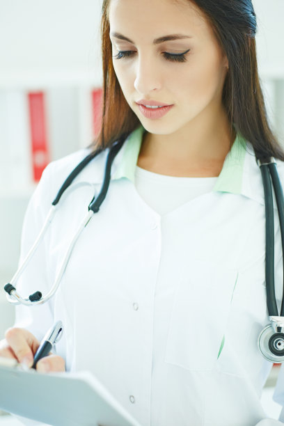 一个女医生在剪贴板上写东西的特写。查房、病人查房、医学计算与统计概念。医生准备好检查病人了图片下载