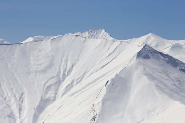 雪白的山峰映衬着湛蓝的天空，雪花在阳光下闪闪发光图片下载