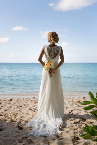 新娘在海边摆姿势，背后捧着婚礼花束图片下载