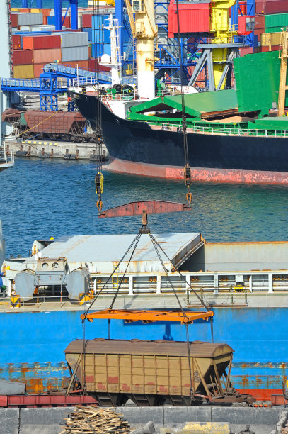 港口起重机下的散装货船和火车图片下载