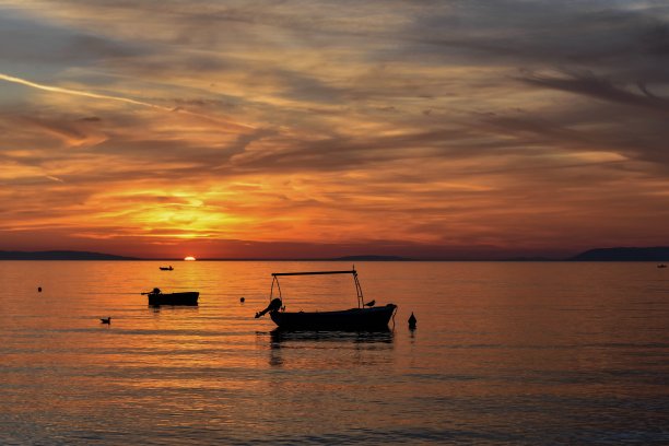 海上日出时前景中船的剪影图片下载