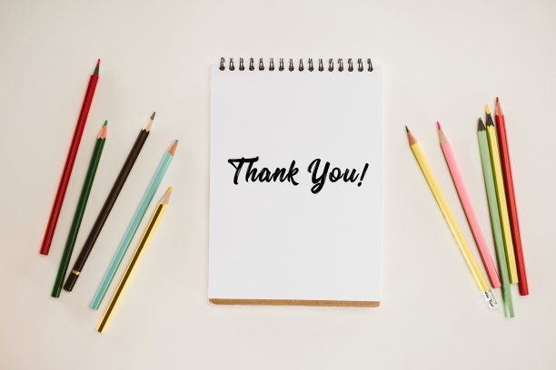 顶视图的记事本与感谢字母和彩色铅笔孤立在白色素材图片
