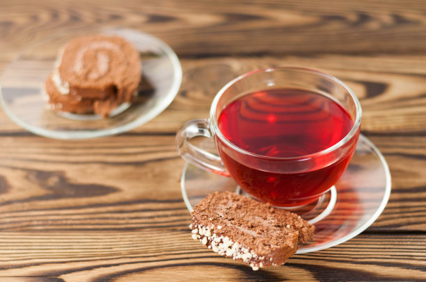 满杯红色美味的覆盆子茶和一片卷派放在古老的木制乡村桌子上的玻璃碟子上图片下载