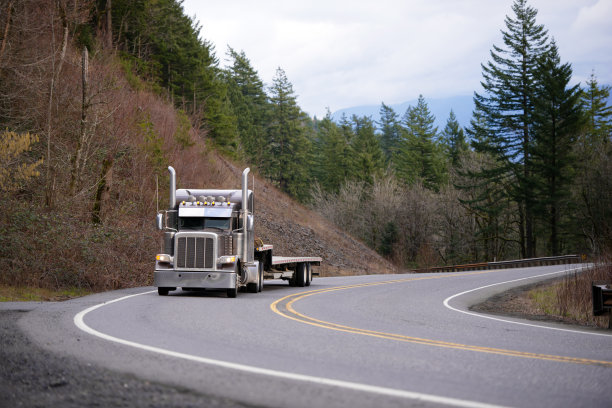 经典的大钻机半挂车与铬配件运输下台阶半挂车在蜿蜒的山路图片下载