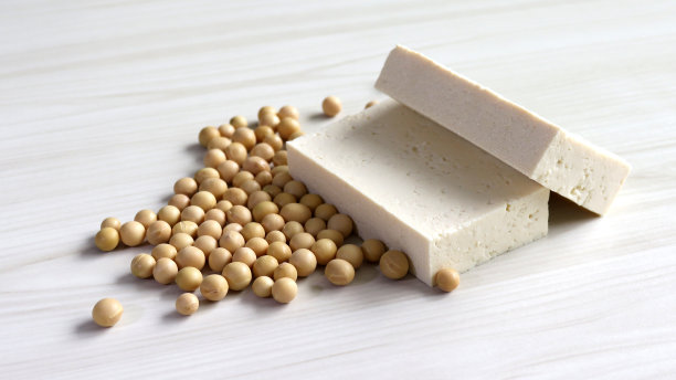 在柔软的木材背景下，点缀着黄豆和两块豆腐。图片下载