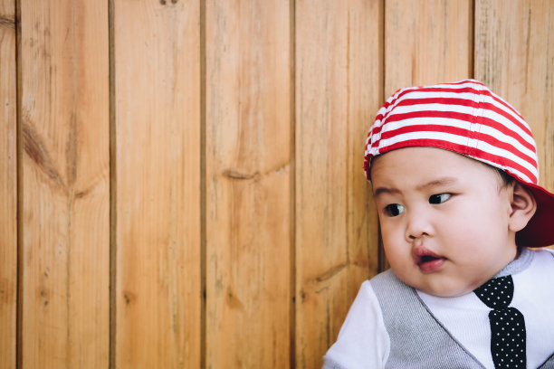 男孩可爱的宝贝看着木墙。图片下载
