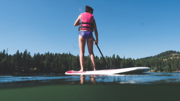少数民族妇女站着在湖上冲浪图片下载