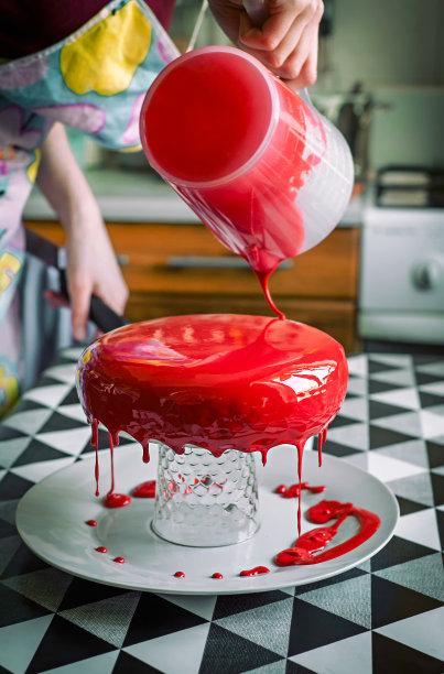 面包师在厨房里浇上了红釉慕斯蛋糕图片下载