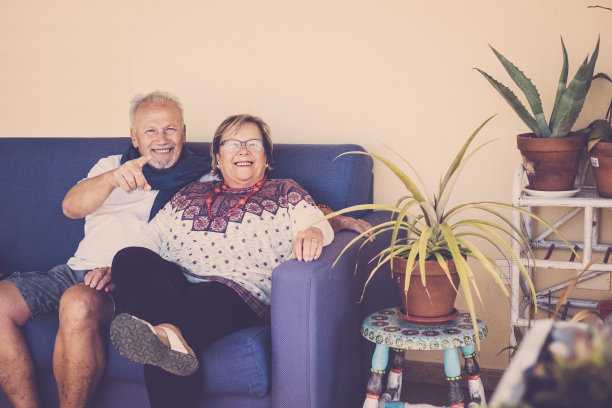 一对快乐的老年夫妇坐在沙发上，周围有植物图片下载