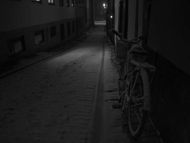 一个孤独的自行车与雪在一个下雪和黑暗的小巷图片下载