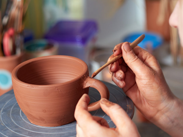 陶器生产工艺。陶工把杯子和杯子的把手连在一起。素材图片