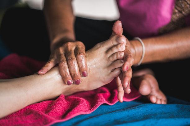 不可辨认的治疗师在水疗中心按摩女人的脚的特写。素材图片