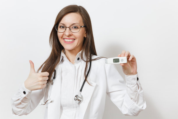 微笑自信的年轻女医生在医疗长袍与听诊器眼镜显示拇指向上，临床电子温度计与正常温度隔离在白色背景。医学概念。图片下载