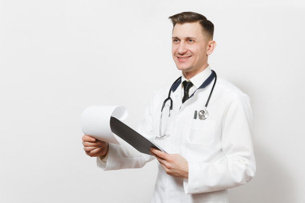 微笑有经验的英俊的年轻医生男子孤立在白色的背景。男医生穿着医疗制服，听诊器健康卡放在记事本文件夹上。医护人员、健康、医学理念。图片下载