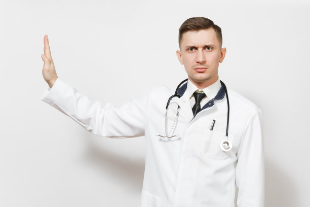 严肃的年轻医生男子孤立在白色的背景。身着医疗制服的男医生，听诊器注视着摄像机，手掌向一边显示停止手势。医护人员健康医学理念。图片下载