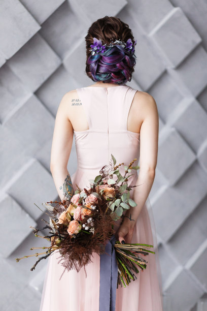 手持婚礼花束的新娘被转到身后。时尚工作室采用灰色背景拍摄图片下载