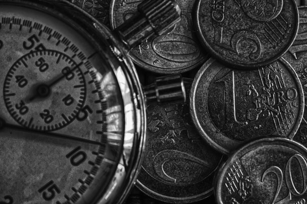 秒表和成堆的硬币放在木桌的背景上图片下载