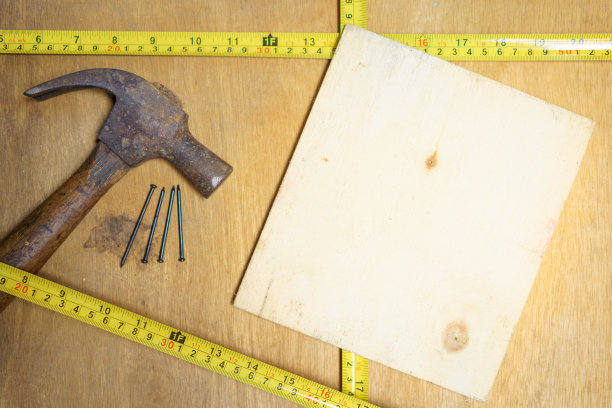 用卷尺将锤子和钉子钉在木桌上，木桌上有白木，用于复制空间和文本，选择性聚焦。静物，复古的概念图片下载