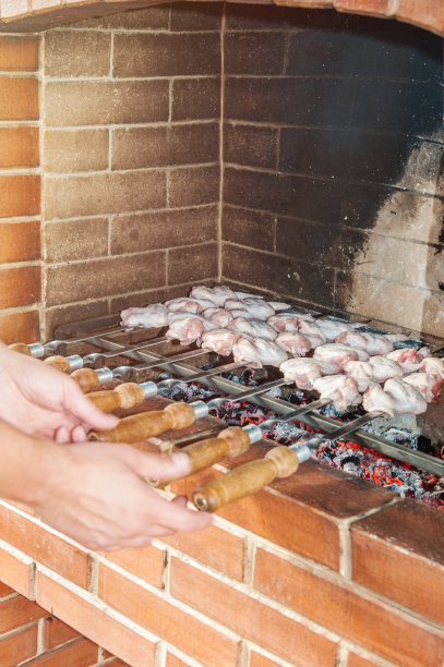 手里拿着一串美味多汁的烤肉串，用烤肉叉在家里的石制烤箱的明火上煎。垂直的框架图片下载