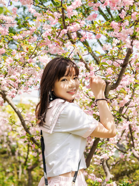 户外肖像美丽的年轻的中国女孩在校服日本风格微笑在樱花树早午餐在春天的花园，美丽，夏天，情感，表达和人们的概念。图片下载