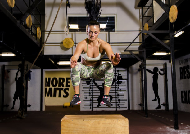 漂亮的女孩/年轻人在健身房的木箱上跳图片下载